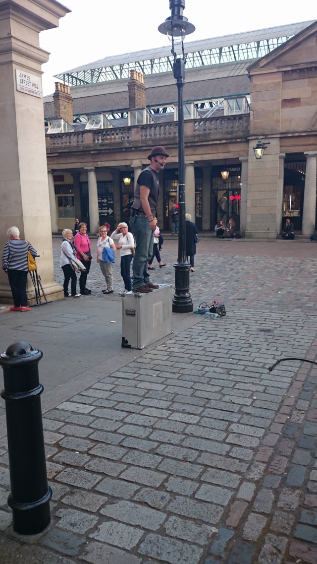 Ein lustiger Mann zeigt einen Kartentrick am Covent Garden